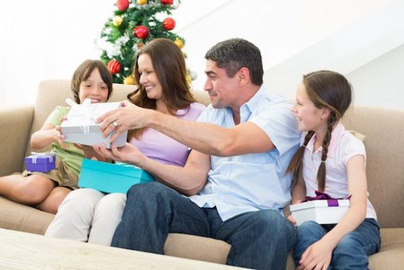 Happy family exchanging Christmas presents at home Oral Hygiene Gift Ideas for Holidays from Alex Bratic Dental Care